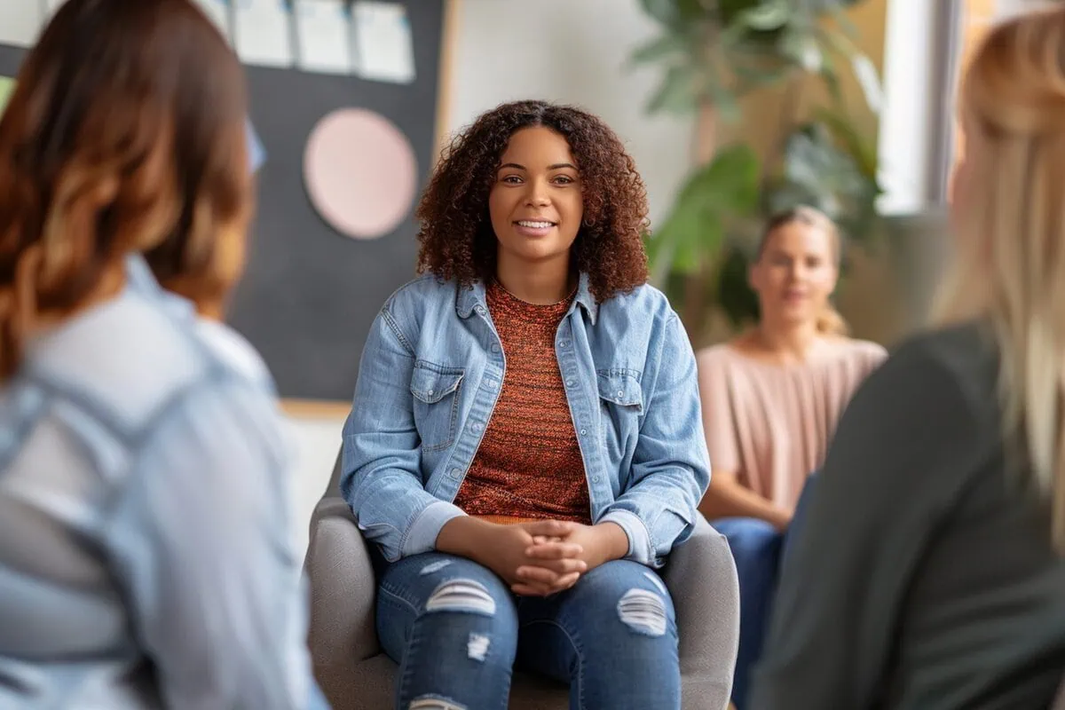 A counselor leading a diverse support group in a welcoming room