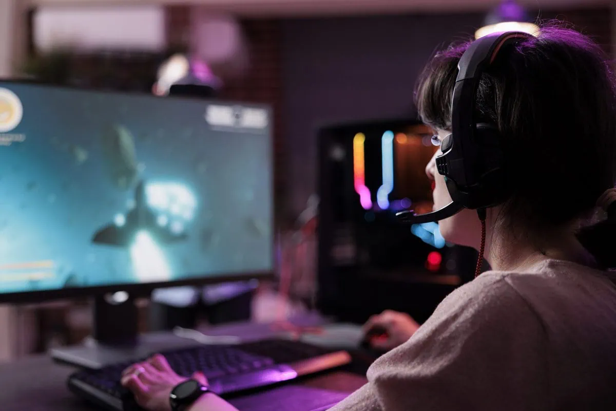 A person wearing a headset and playing a video game at a computer