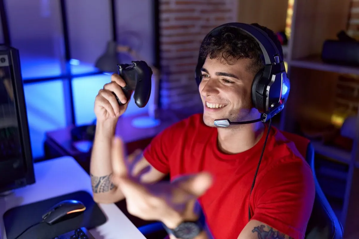 A smiling person holding a game controller during an online session